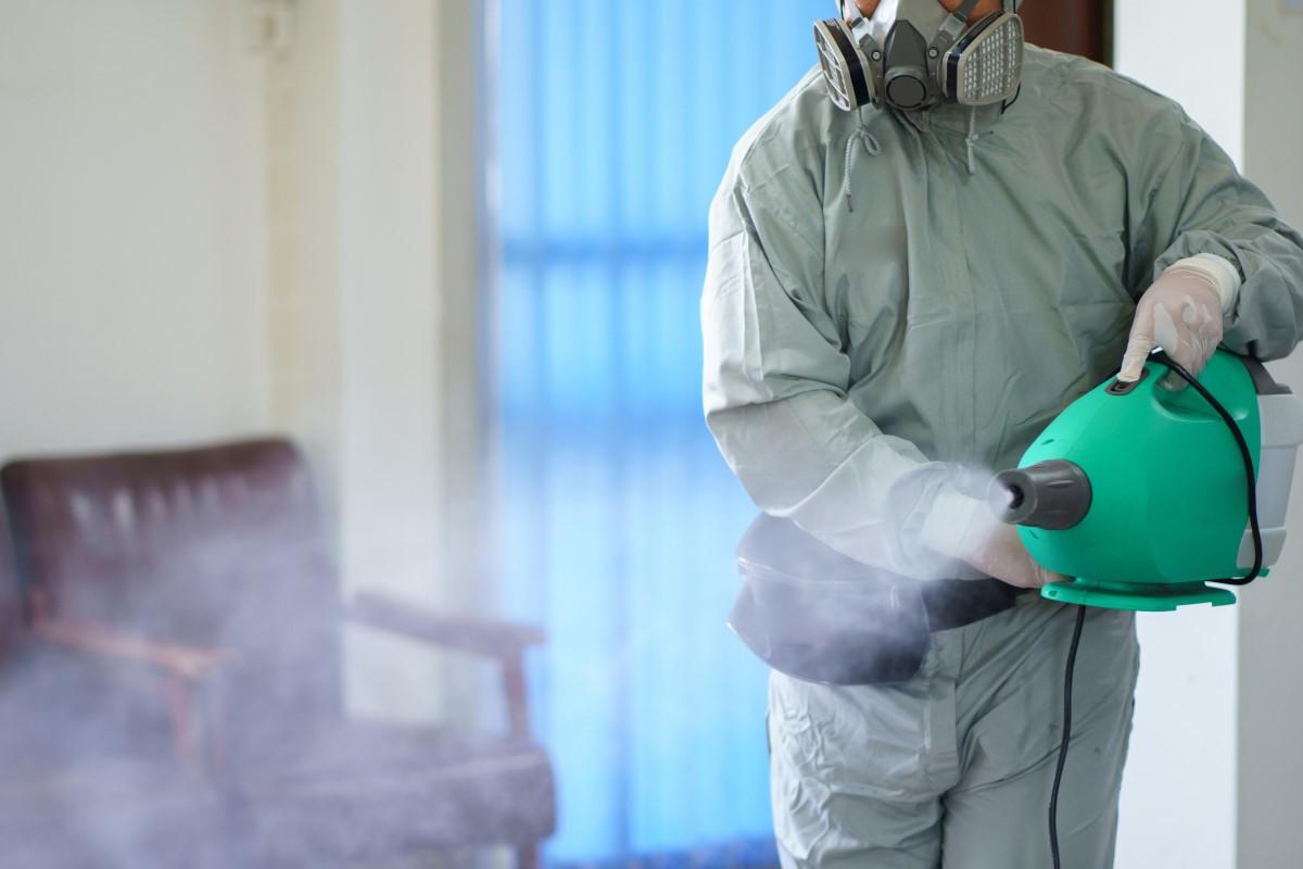 person wearing protective suit and mask during a disinfecting